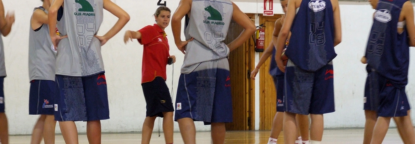 Entrenadora da indicaciones a jugadores de baloncesto en la cancha.