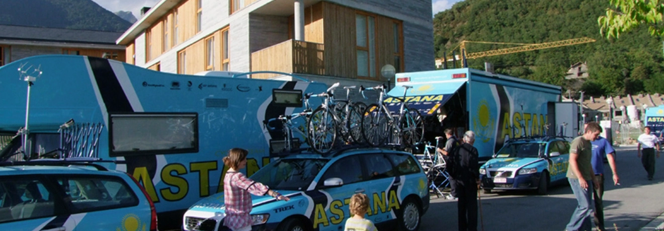 Camiones y coches del equipo Astana con bicicletas en un entorno monta&ntilde;oso.
