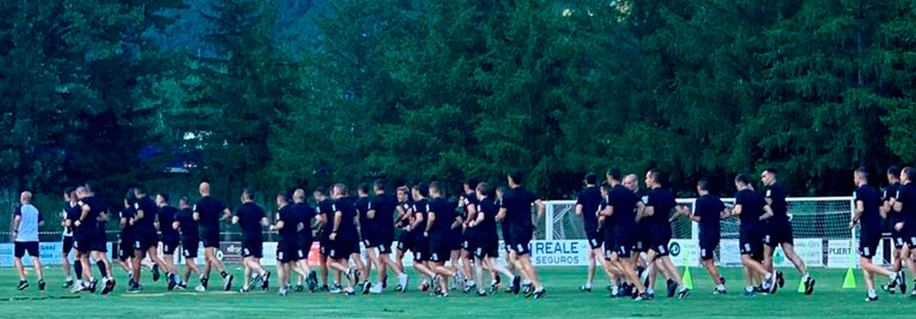 Grupo de personas corriendo en un campo rodeado de &aacute;rboles.