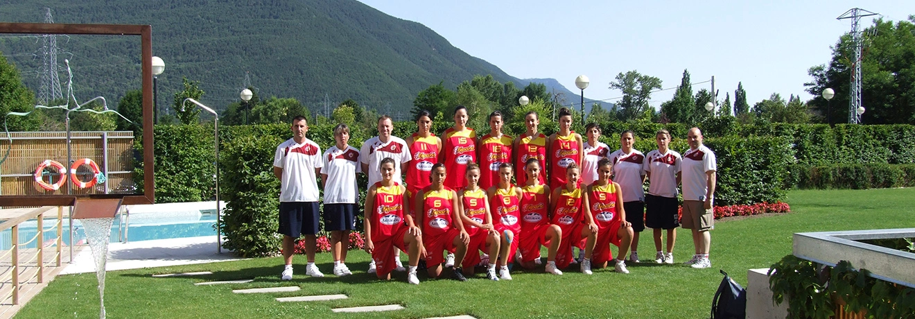 Equipo de baloncesto posando al aire libre en un jard&iacute;n con monta&ntilde;as al fondo.