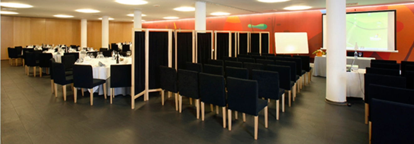 Sala de conferencias con asientos y mesas arregladas para un evento.