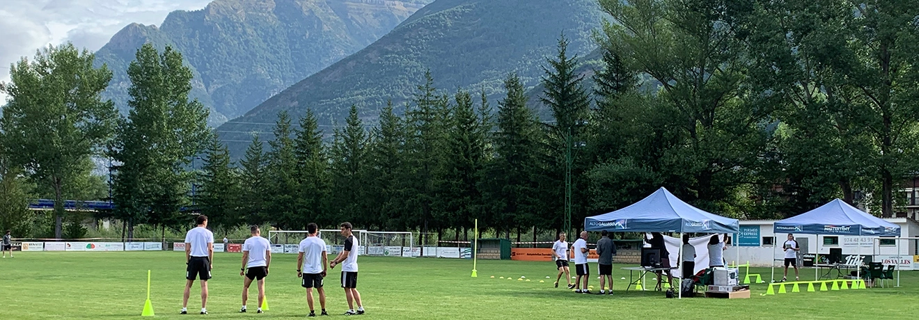 Grupo en un campo de deportes al aire libre, con monta&ntilde;as al fondo.