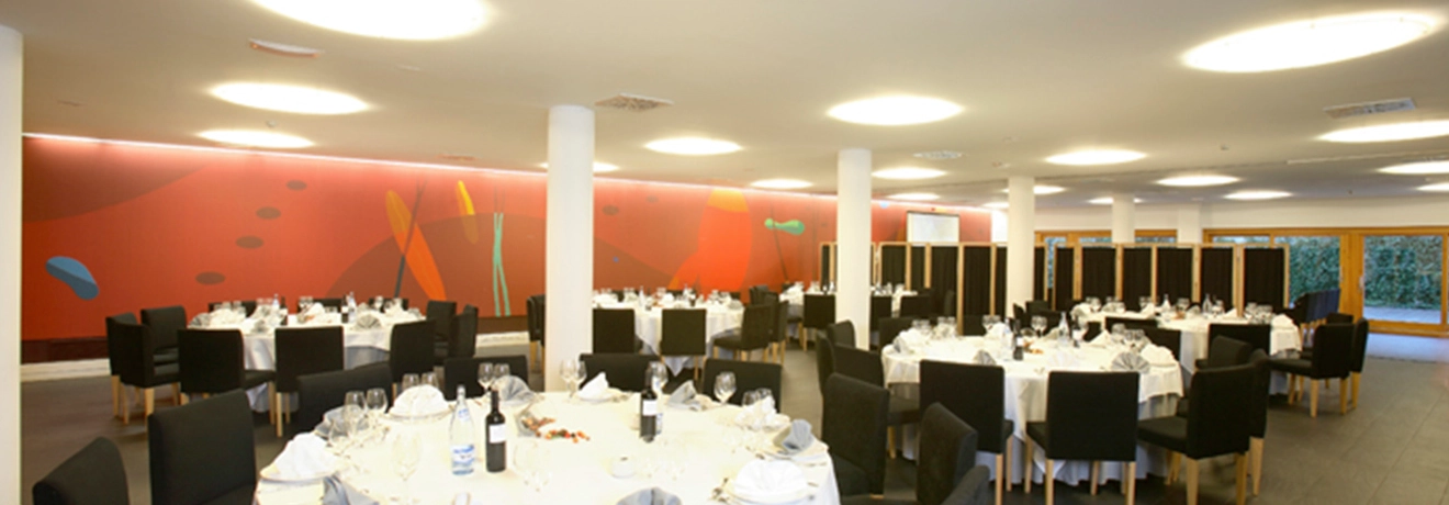 Sal&oacute;n de banquetes elegante con mesas redondas y sillas negras.