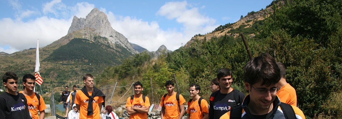 Grupo de personas en la monta&ntilde;a, algunas con camisetas naranjas y negras.