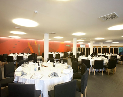 Sal&oacute;n de banquetes con mesas redondas y sillas negras.