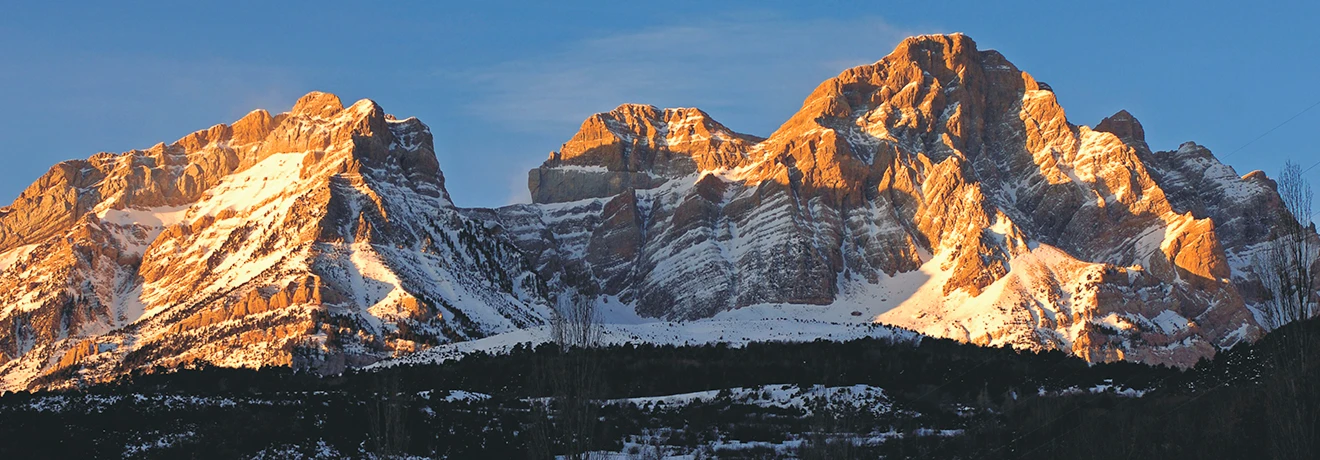 Monta&ntilde;as nevadas iluminadas por el sol al atardecer.