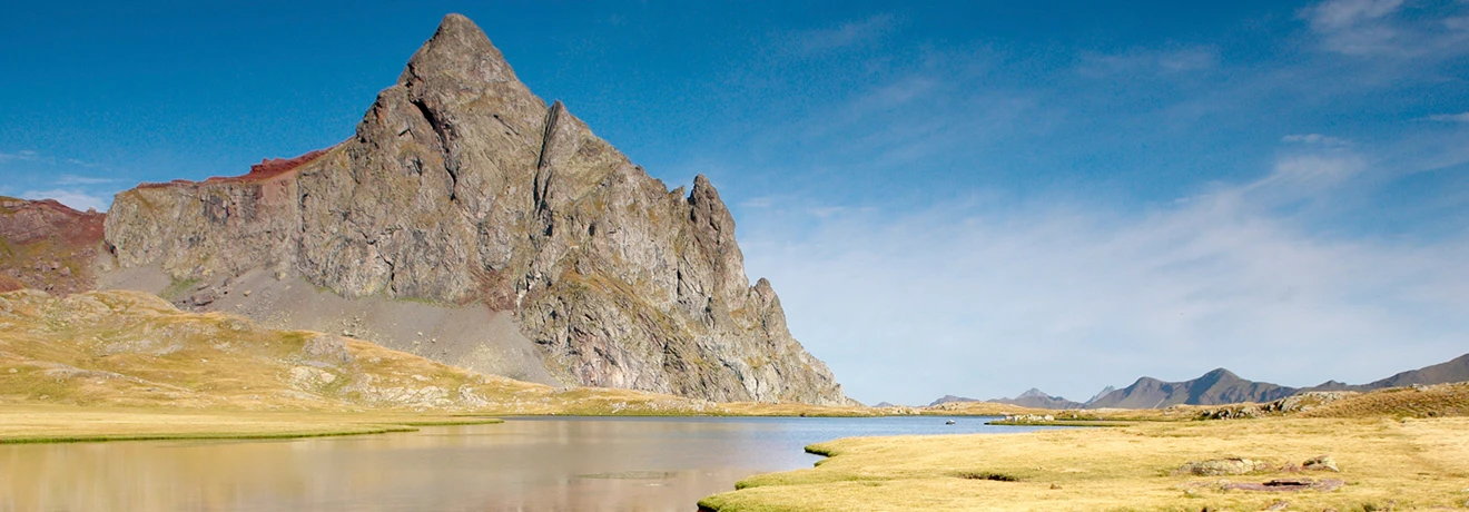 Monta&ntilde;a junto a un lago con cielo despejado y paisaje seco.