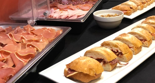 Bocadillos y embutidos en bandejas sobre una mesa.