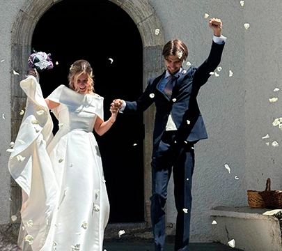 Pareja reci&eacute;n casada saliendo de una iglesia, rodeada de p&eacute;talos.