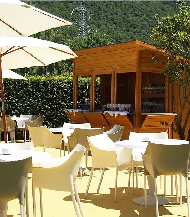 Sillas y mesas blancas al aire libre junto a un bar de madera.