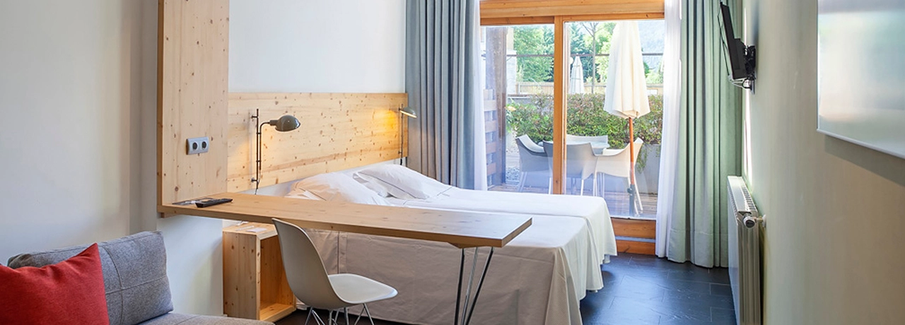 Habitación moderna con cama doble, escritorio y acceso a un patio exterior.