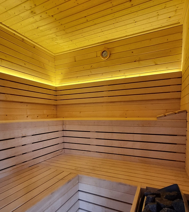 Sauna de madera con bancos y luz c&aacute;lida bajo los asientos.