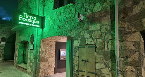 Entrada de un edificio de piedra con letrero verde que dice "Tierra Boutique".