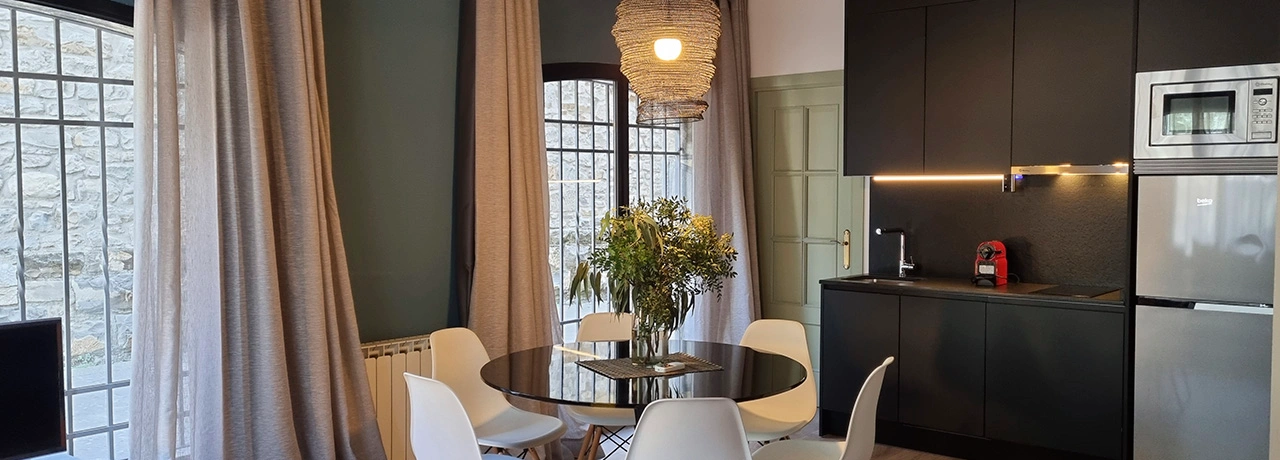 Comedor moderno con mesa redonda y cocina integrada en tonos oscuros.