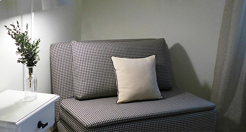 Sill&oacute;n a cuadros con coj&iacute;n beige junto a mesa con florero.