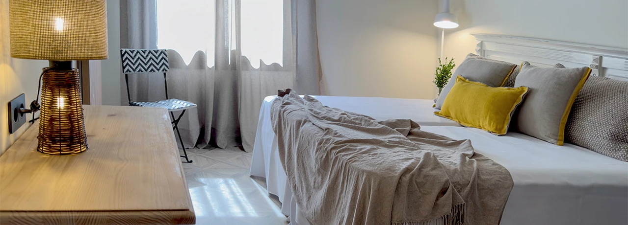 Habitación acogedora con cama, lámparas tenues y cortinas grises.