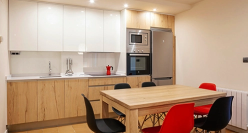 Cocina moderna con mesa y seis sillas, electrodom&eacute;sticos y acabados de madera.