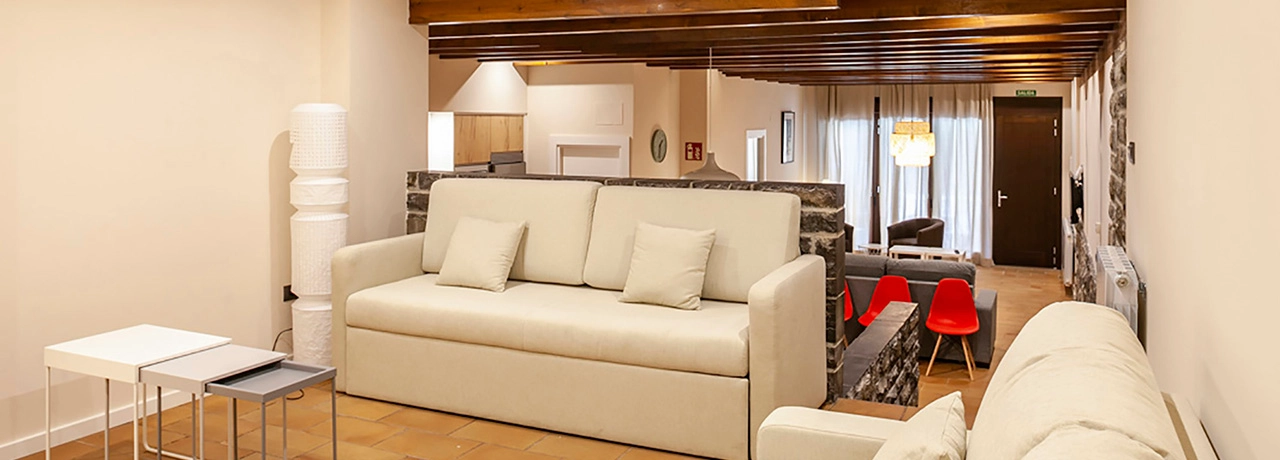 Sala de estar moderna con sof&aacute;s y sillas, iluminaci&oacute;n c&aacute;lida.