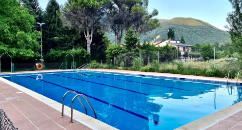 Piscina al aire libre rodeada de &aacute;rboles y monta&ntilde;as al fondo.