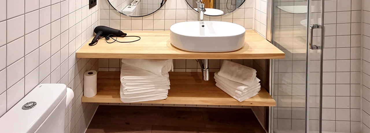 Baño moderno con lavabo, espejo, secador y toallas en estante de madera.