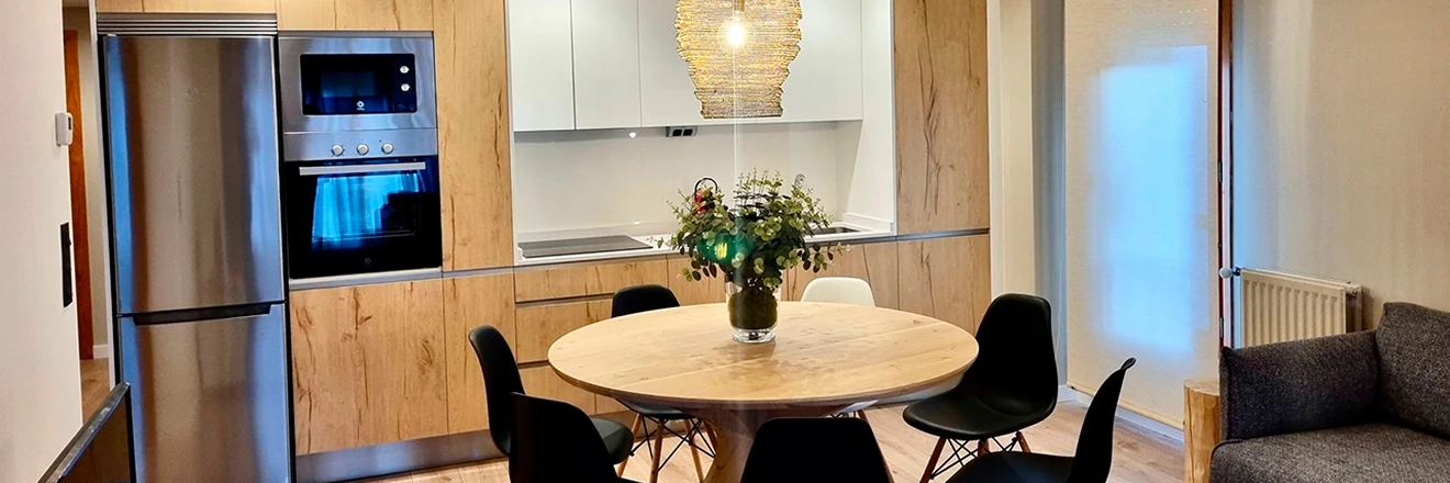 Cocina moderna con mesa redonda, sillas y decoraci&oacute;n floral.