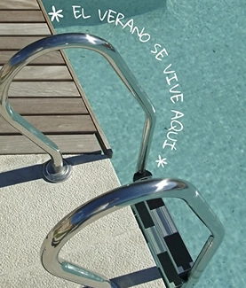 Escaleras de piscina con texto "El verano se vive aquí".