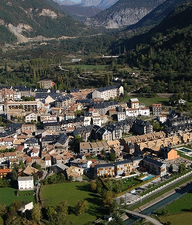 Vista aérea de un pueblo rodeado de montañas y vegetación.
