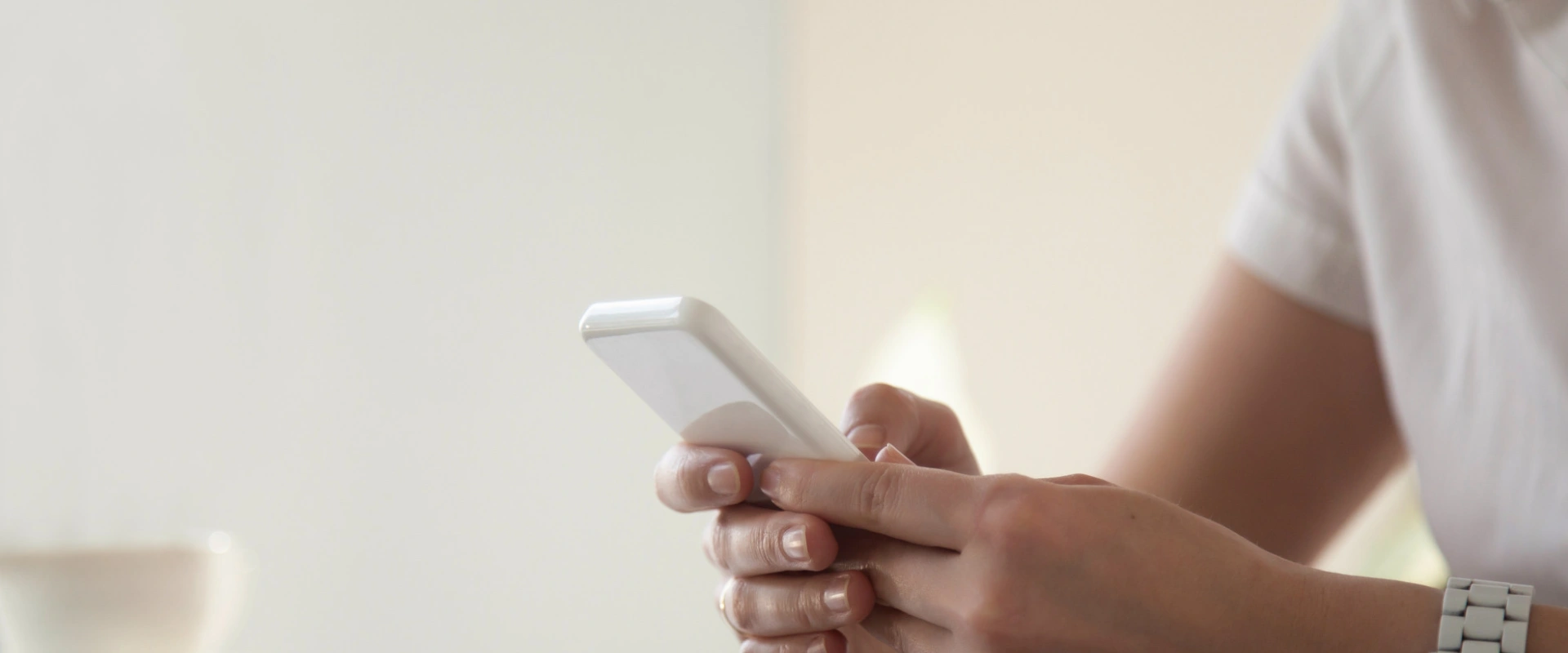 Persona usando un tel&eacute;fono m&oacute;vil blanco.