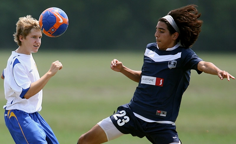 Jugadores de f&uacute;tbol en acci&oacute;n, uno cabecea el bal&oacute;n en el aire.