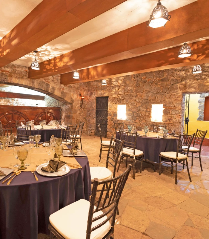 Sal&oacute;n r&uacute;stico con mesas redondas vestidas, listo para un evento elegante.