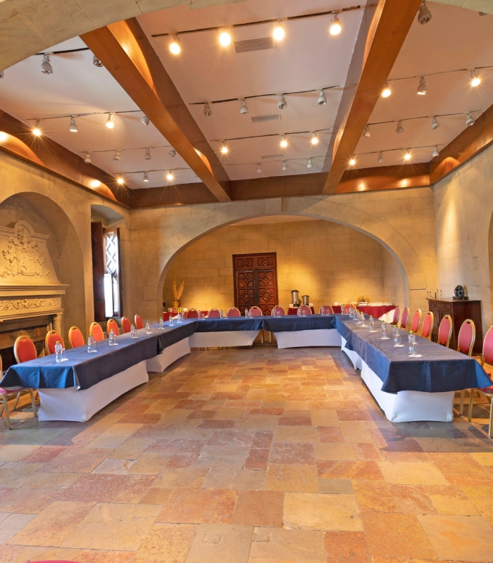 Sala de reuniones elegante con mesas en forma de U y sillas rojas.