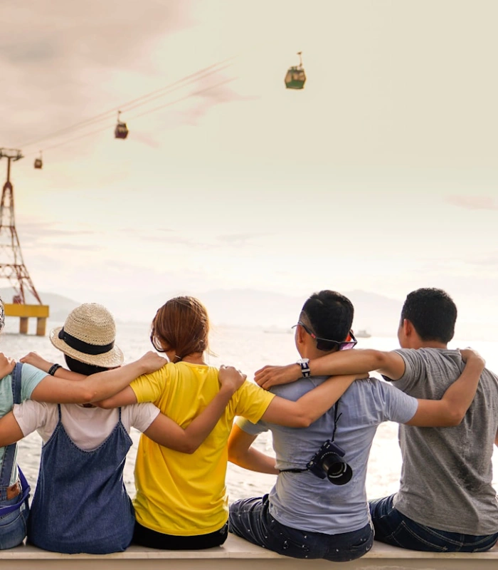 Grupo de amigos se abrazan viendo telef&eacute;ricos sobre el agua.