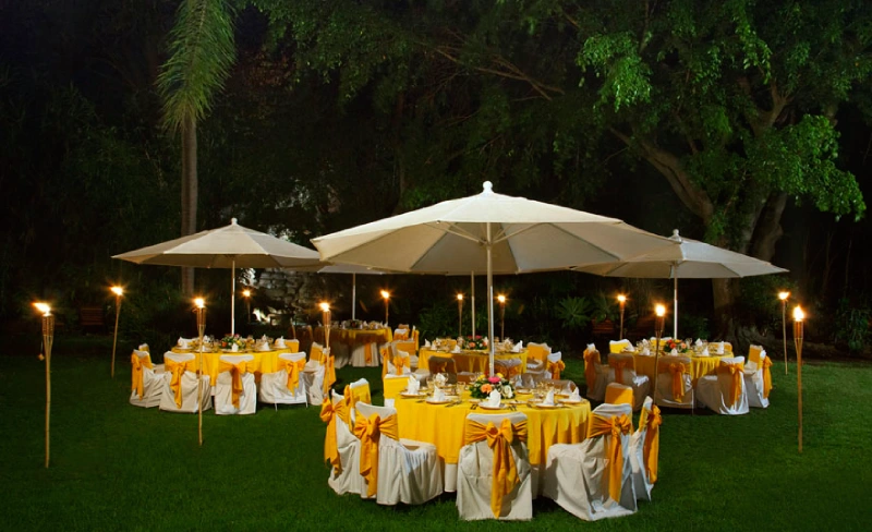 Mesas al aire libre decoradas con manteles amarillos y sillas con lazo.