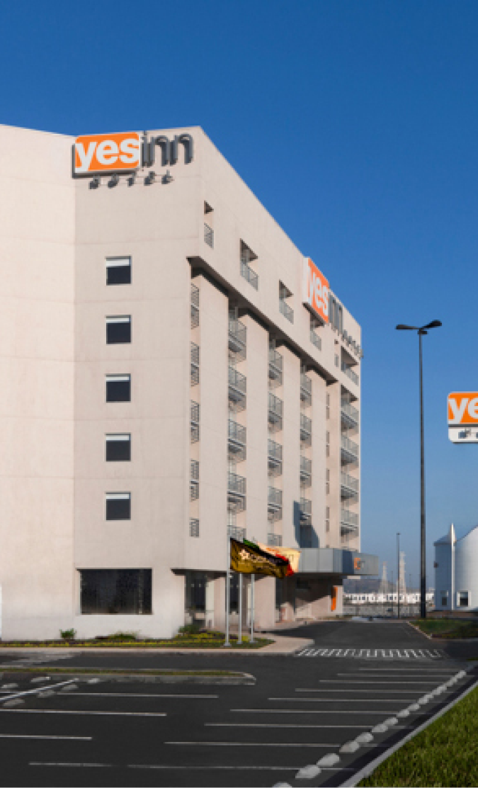 Edificio de hotel moderno con cielo azul claro y letrero "yes inn".