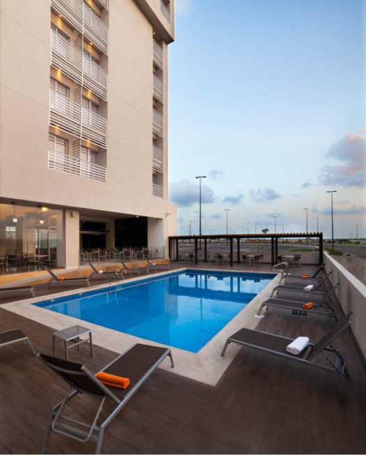Piscina en la terraza de un edificio moderno con tumbonas alrededor.