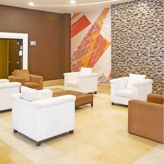 Sala de espera con sillones blancos y marrones, decoraci&oacute;n moderna y luminosa.