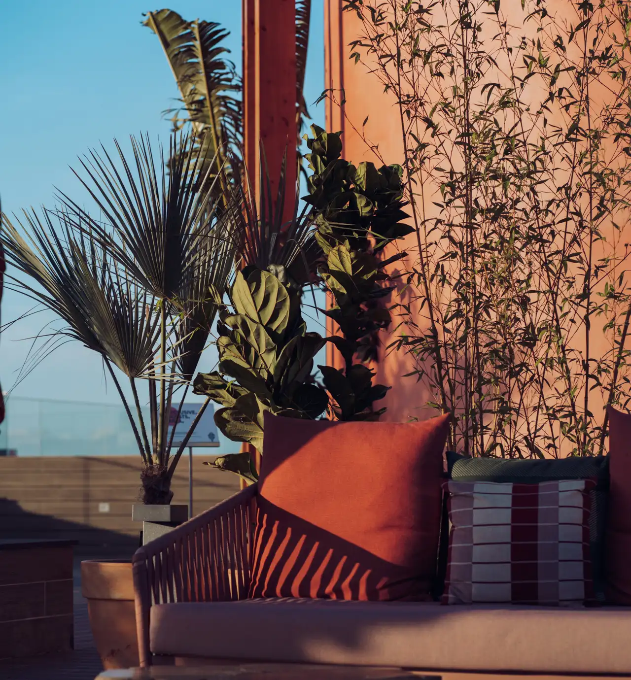 Poltronas e almofadas ao ar livre com plantas e sombra ao sol.