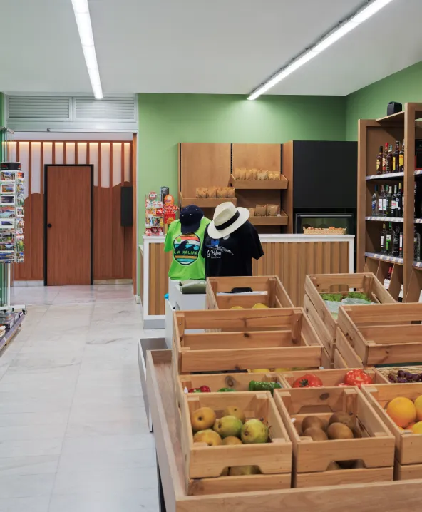 Tienda con frutas en cajas de madera, estantes y ropa en exhibici&oacute;n.