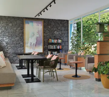 Sala moderna con sillones, plantas y un cuadro grande en la pared de piedra.