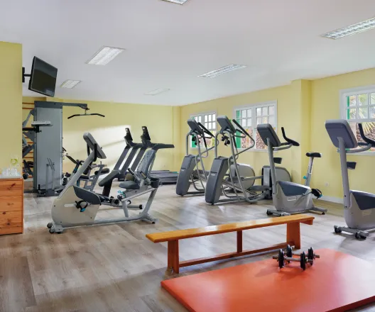 Gimnasio con bicicletas est&aacute;ticas y m&aacute;quinas de ejercicio.