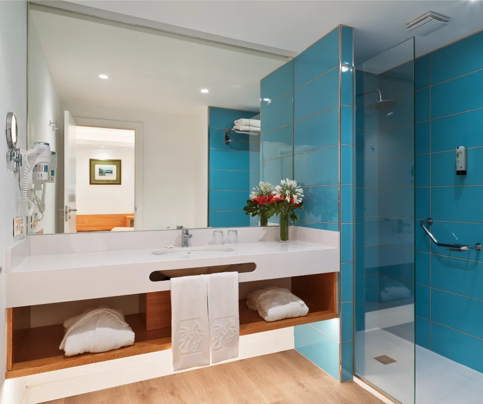 Ba&ntilde;o moderno con paredes azules, lavabo blanco y ducha de vidrio.