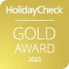 Premio de Oro HolidayCheck 2023 en fondo dorado.