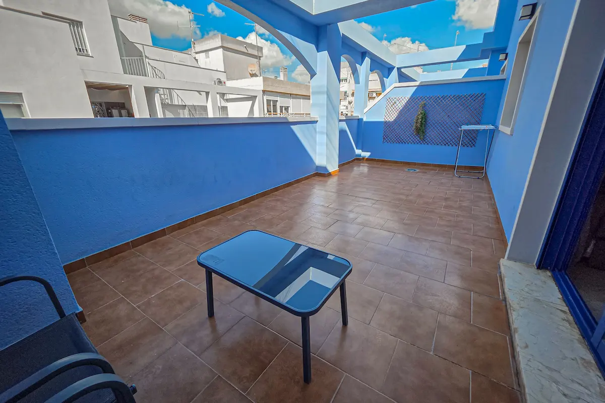 Terraza azul con mesa de vidrio y cielos despejados.