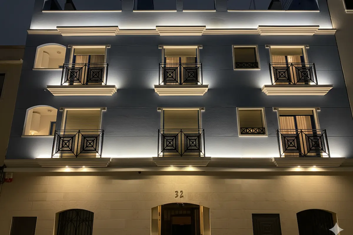 Edificio iluminado de noche con balcones y el número 32 en la entrada.