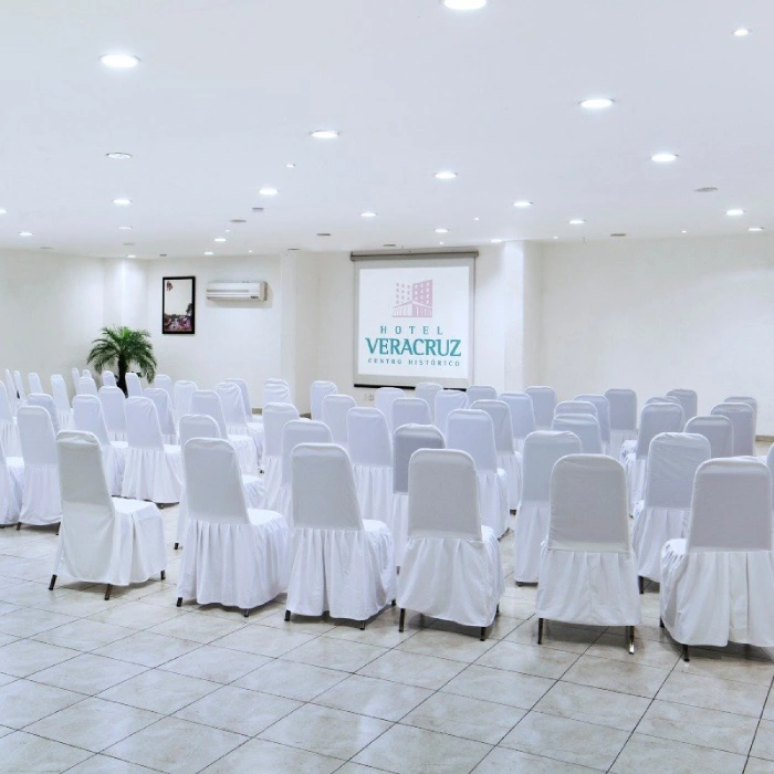 Sala de conferencias con sillas blancas y proyector en Hotel Veracruz.