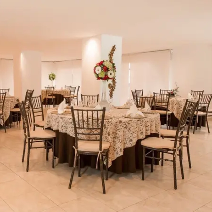 Mesas redondas decoradas para un evento, con sillas y flores.