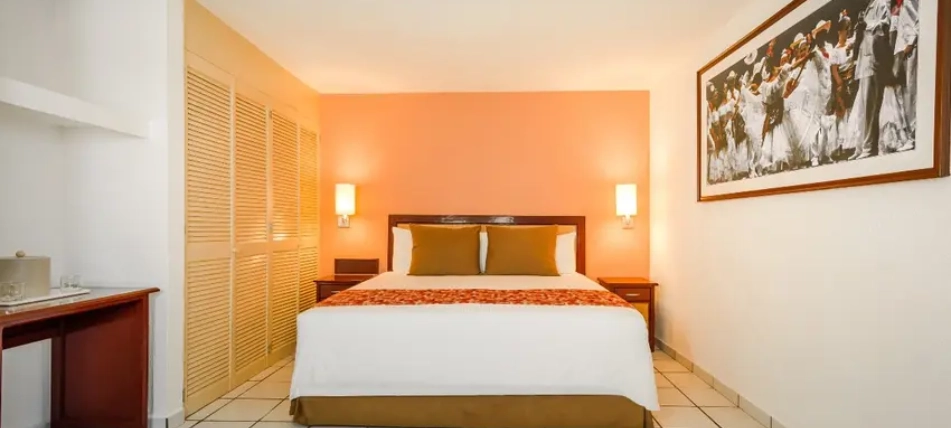 Habitaci&oacute;n de hotel con cama matrimonial y decoraci&oacute;n acogedora.