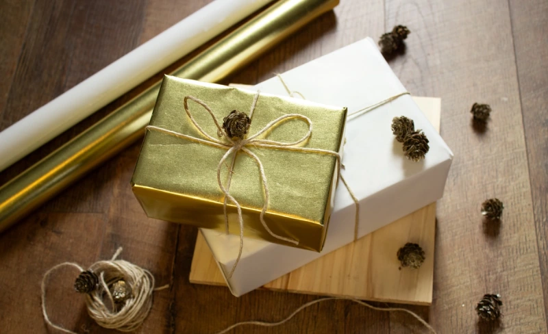Regalos envueltos con papel dorado y blanco, decorados con pi&ntilde;as peque&ntilde;as.