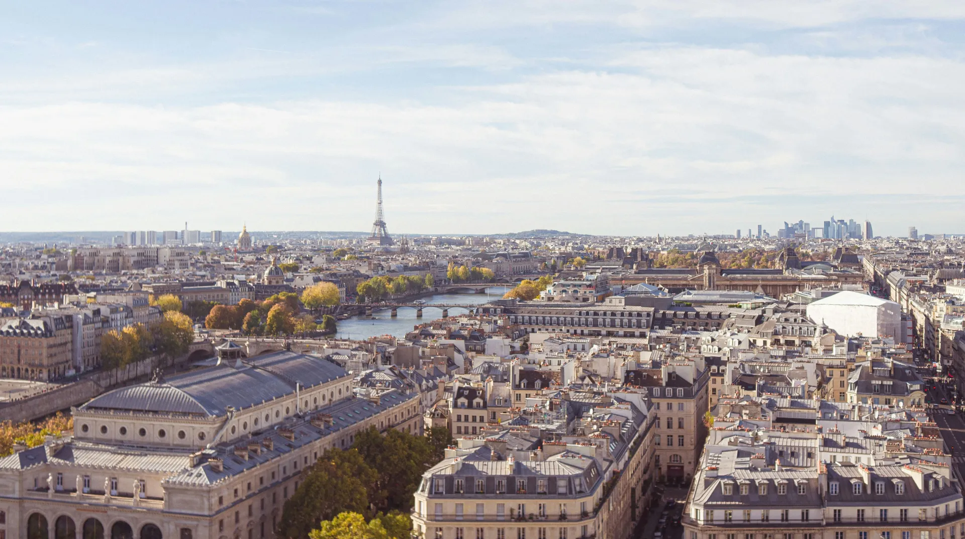 Vue a&eacute;rienne de Paris avec la tour Eiffel et la Seine sous un ciel d&eacute;gag&eacute;.