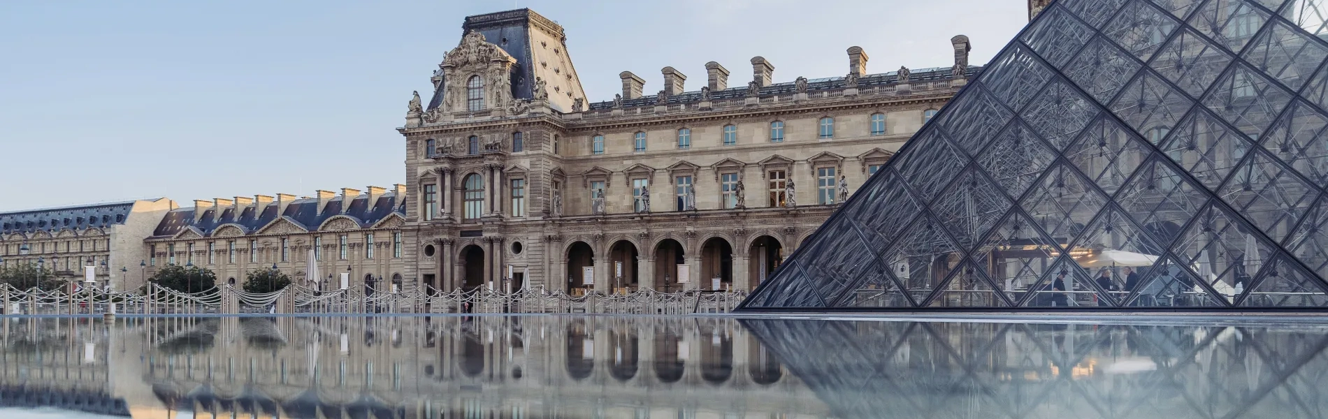 Pyramide de verre devant le mus&eacute;e historique avec reflets sur l'eau.